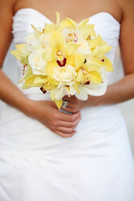 robe de mariée blanche, bustier et un bouquet de lys jaunes et de roses jaune 