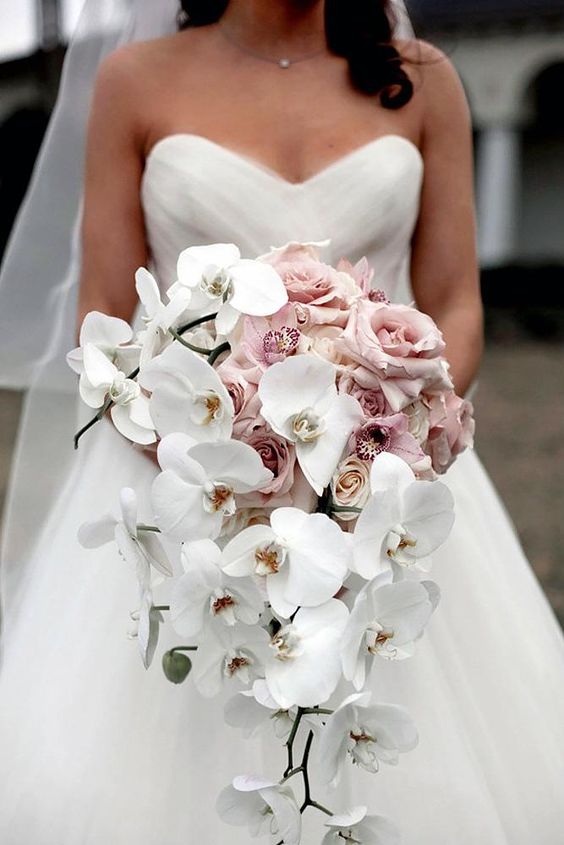 robe de mariée blanche bustier et un bouquet d'orchidées blanches, des roses rose 