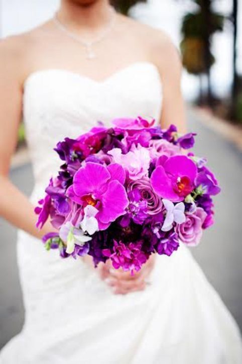 robe de mariée blanche bustier et un bouquet d'orchidées mauves et de fleurs mauves