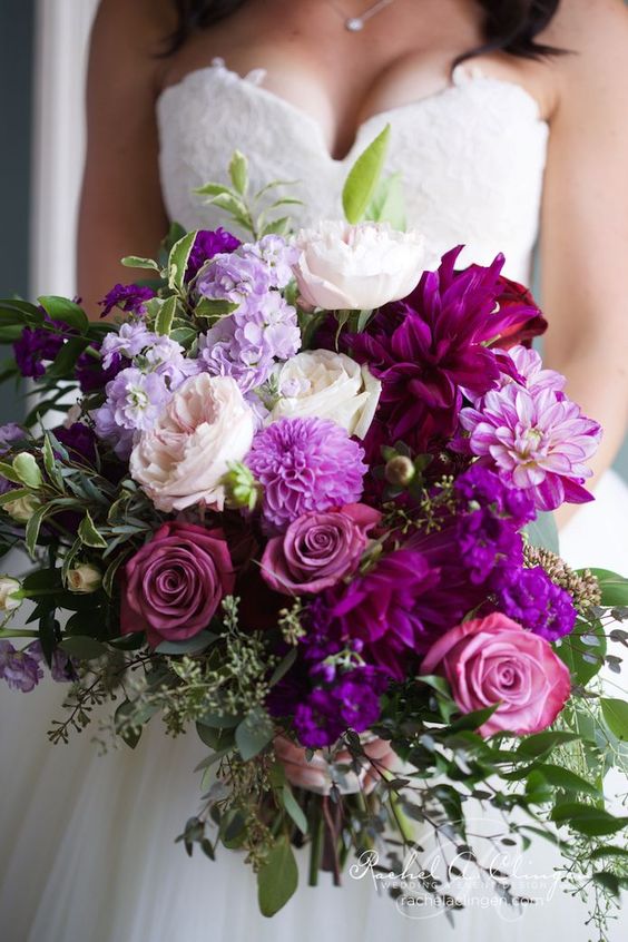 Mariée dans une robe blanche bustier avec un bouquet de roses mauves et de fleurs mauves et blanches