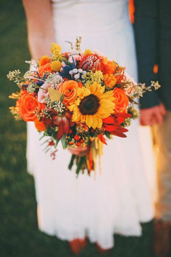 Mariée dans une robe blanche courte avec un bouquet de roses orange et de fleurs oranges