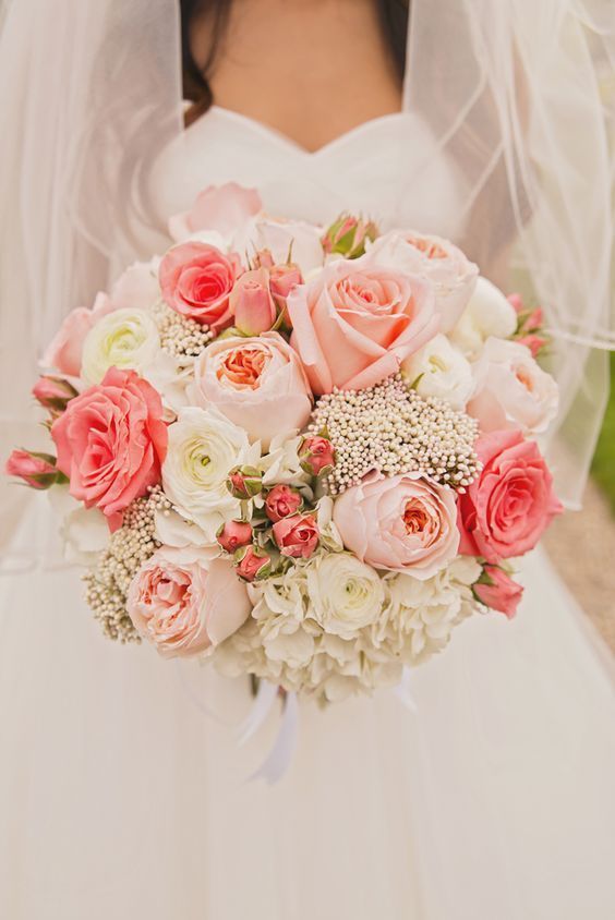 Mariée dans une robe blanche avec un voile avec un bouquet de roses roses et de fleurs roses