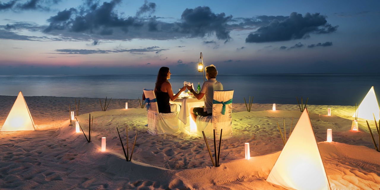 Jeunes mariés profitant d'un diner aux chandelles sur la plage lors de leur lune de miel
